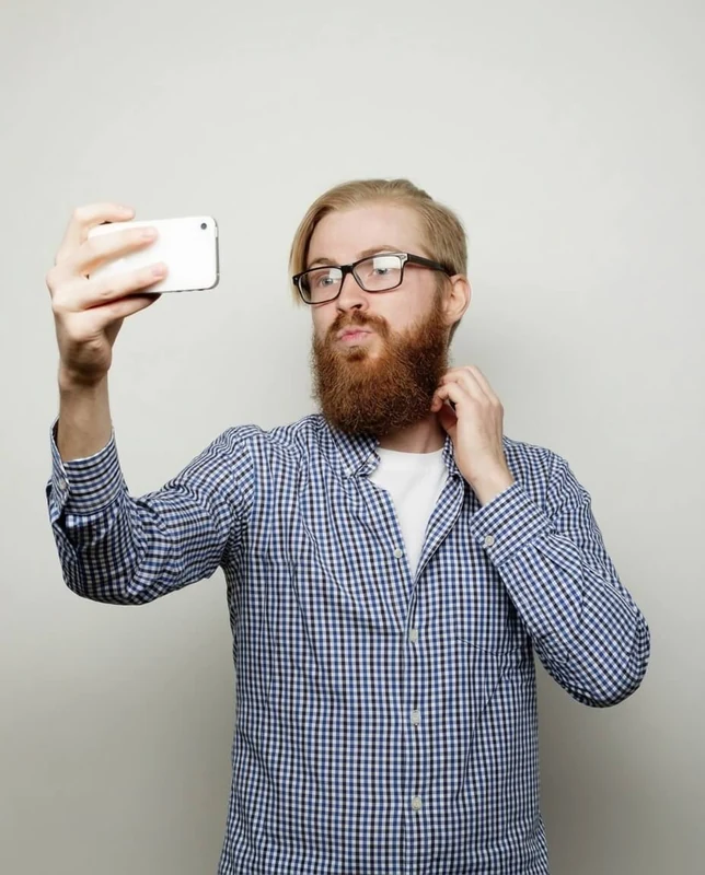 A bearded man holding up a phone for a selfie